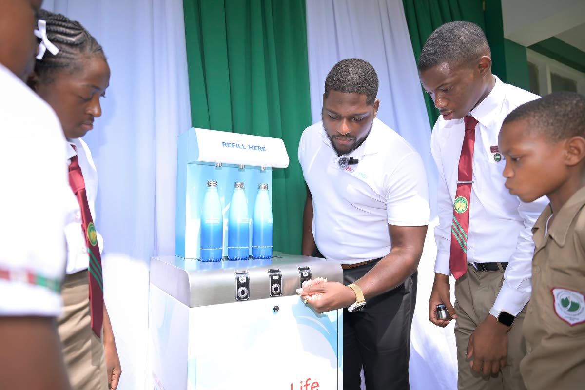 Students of Oberlin High School observe as Project Lead at Newport Water Limited, Sheridan Greaves (centre), demonstrates the use of the institution’s newly installed hydration station during a handover ceremony at the St Andrew-based institution on Frid