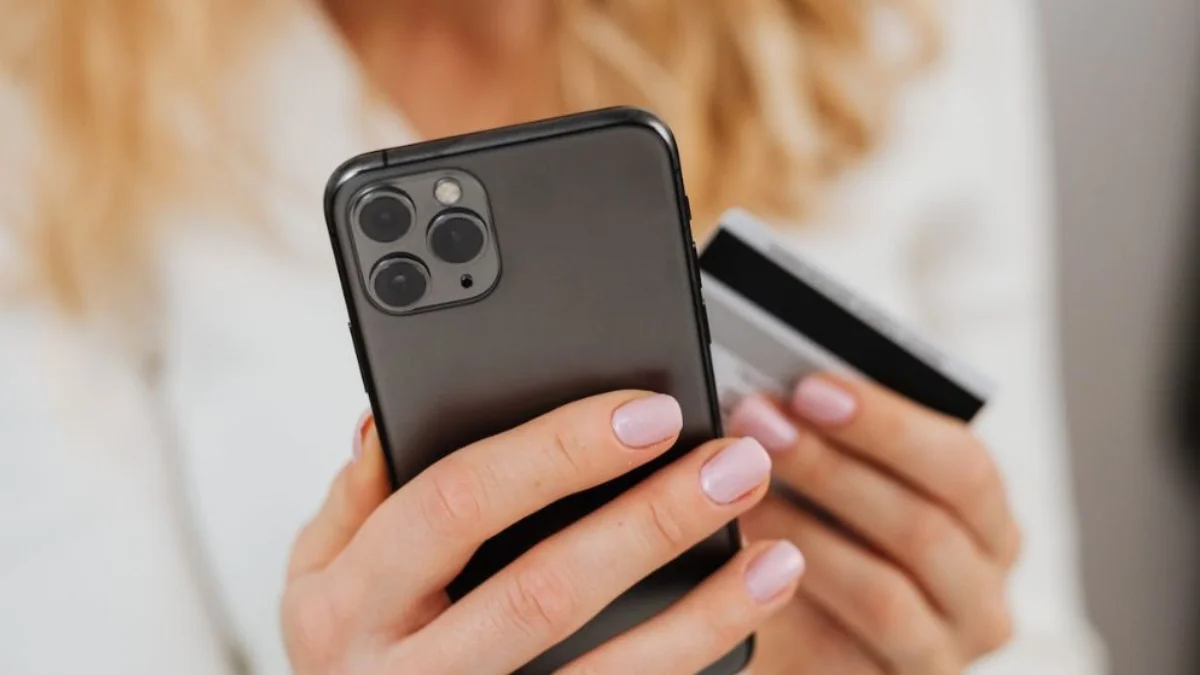 Pessoa segurando celular e cartão de crédito