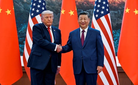 Donald Trump and Xi Jinping shake hands in front of US and Chinese flags