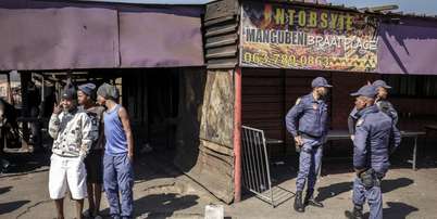Policiais sul-africanos cercam um estabelecimento onde dez pessoas morreram em um tiroteio na madrugada deste domingo (27), no município de Lwandle, nos arredores da Cidade do Cabo. Foto: AFP - GIANLUIGI GUERCIA / RFI