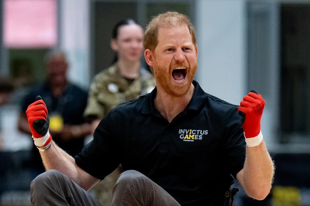 Foto colorida de homem com blusa preta dos Jogos Invictus torcendo - Metrópoles