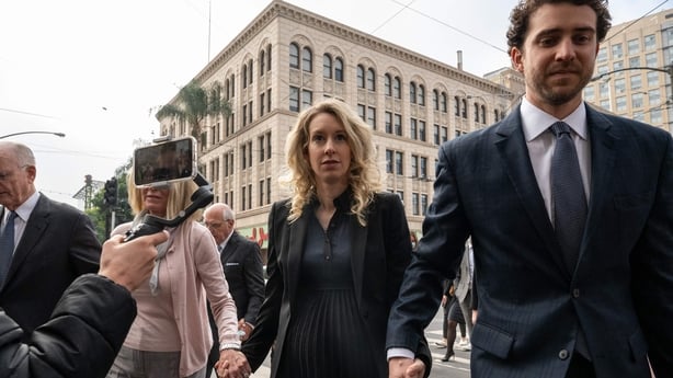 Elizabeth Holmes (C) walks with her mother Noel Holmes and partner Billy Evans into the federal courthouse for her sentencing hearing on 18 November 2022 in San Jose, California.
